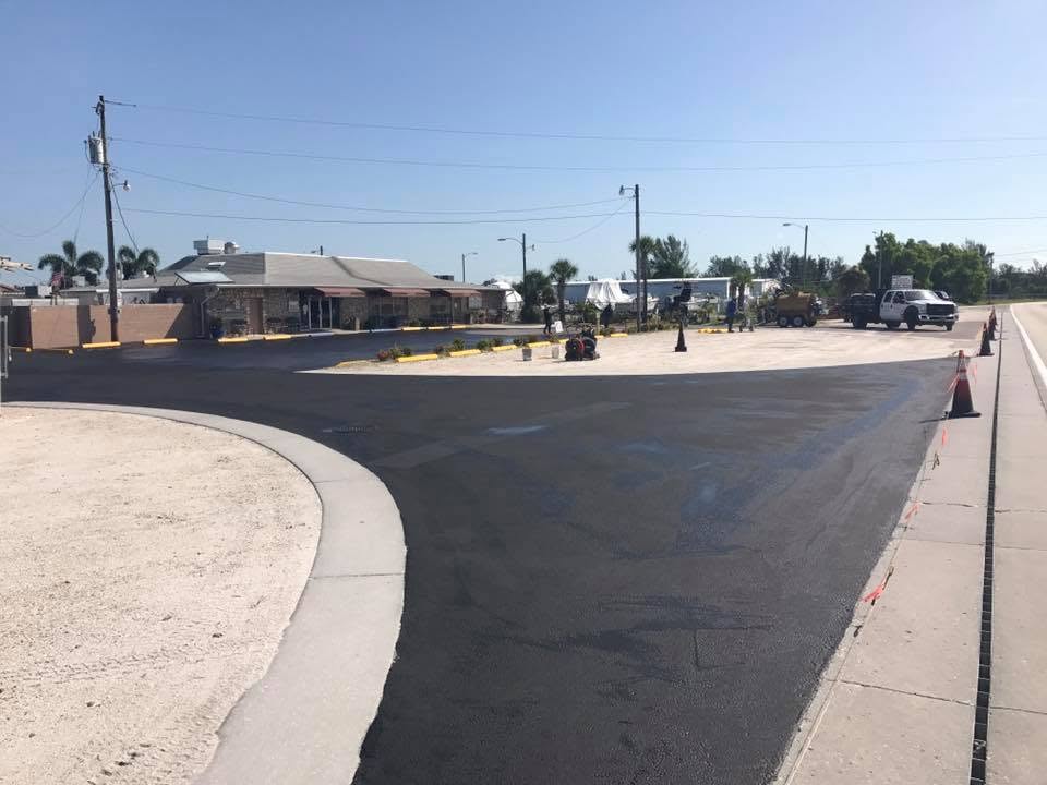 Freshly sealcoated commercial lot along the roadway with crew and truck on site