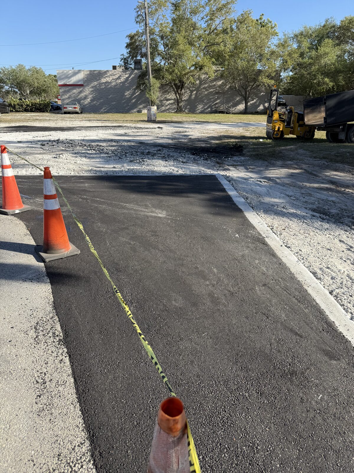 Freshly paved asphalt drive lane with safety cones and caution tape